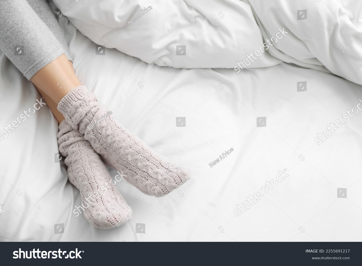 stock-photo-woman-wearing-warm-socks-in-comfortable-bed-closeup-space-for-text-2255691217